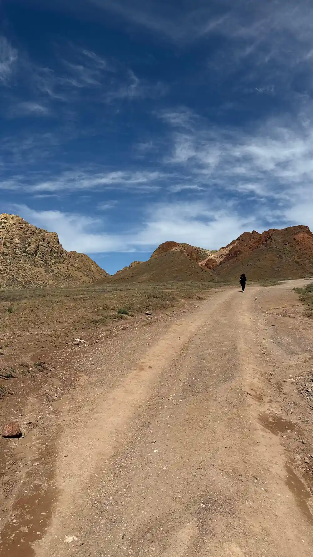 Dirt road through arid hills with person walking distant