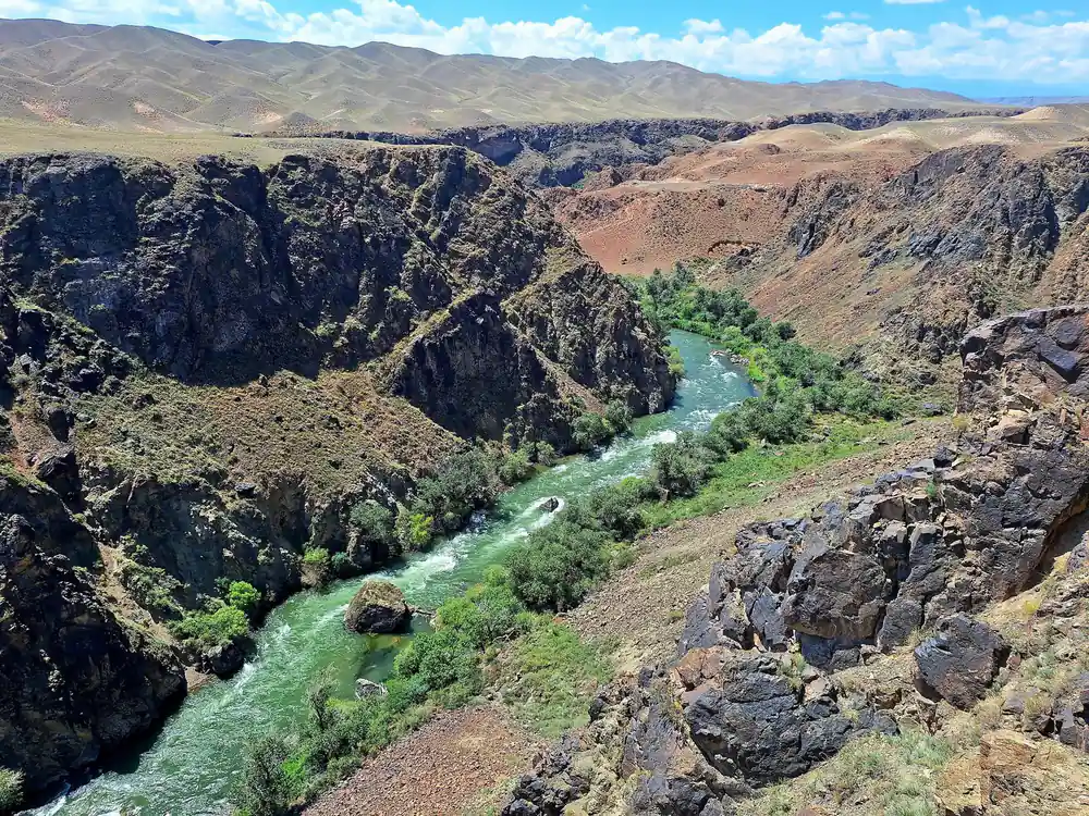 Green river flowing through desert canyon with rock walls