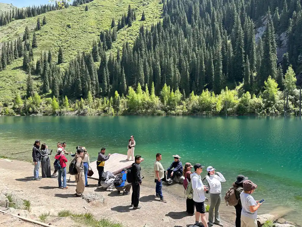 Group of people gathered at turquoise alpine lake