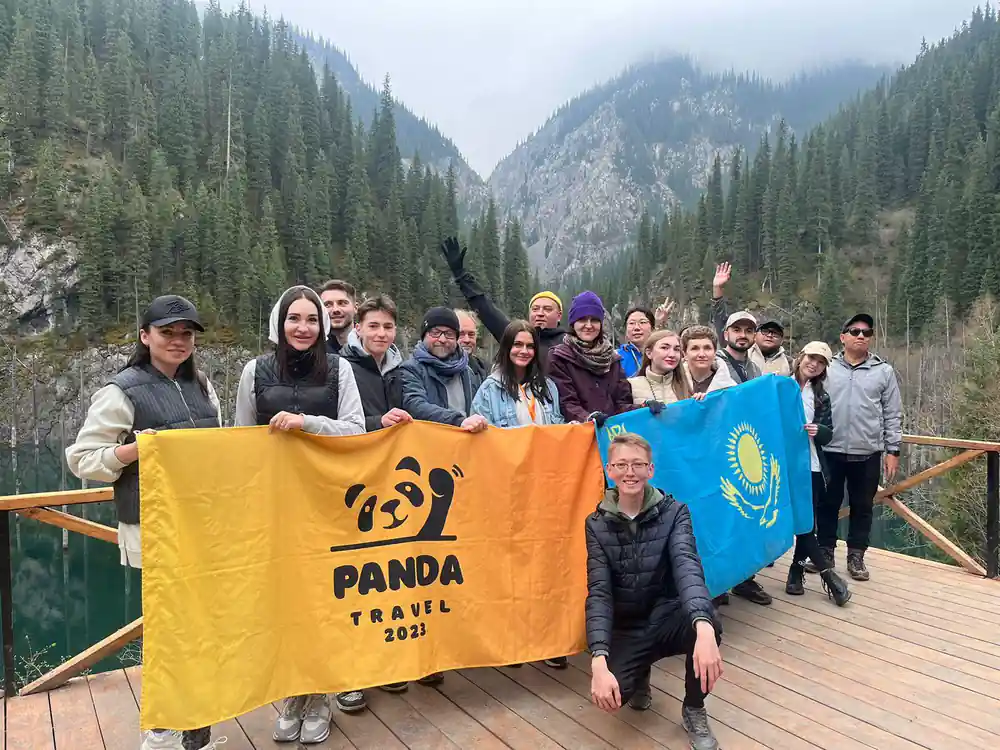 Group of people holding Panda Trail flag in mountain valley