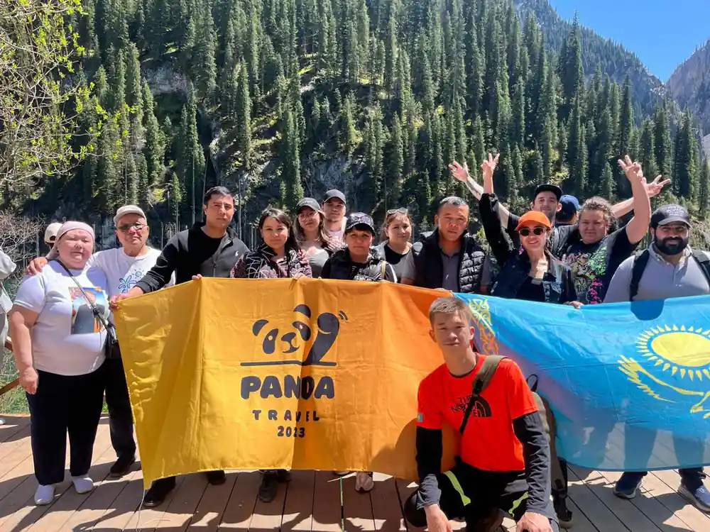 Group of people with Panda Trail flag in mountain valley with forest