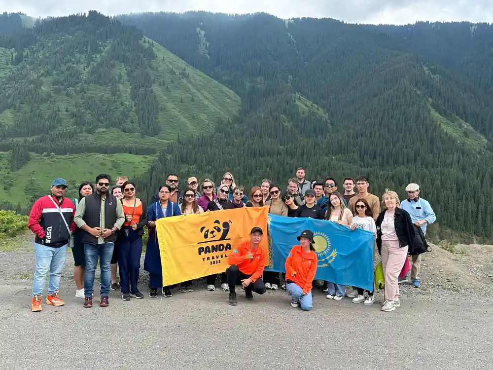 Group of people with Panda Trail flag on wooden platform in valley