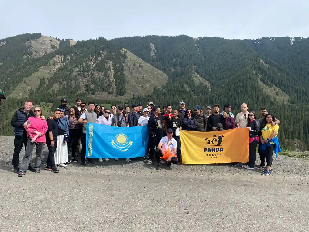 Group of tourists in mountain valley holding flags together