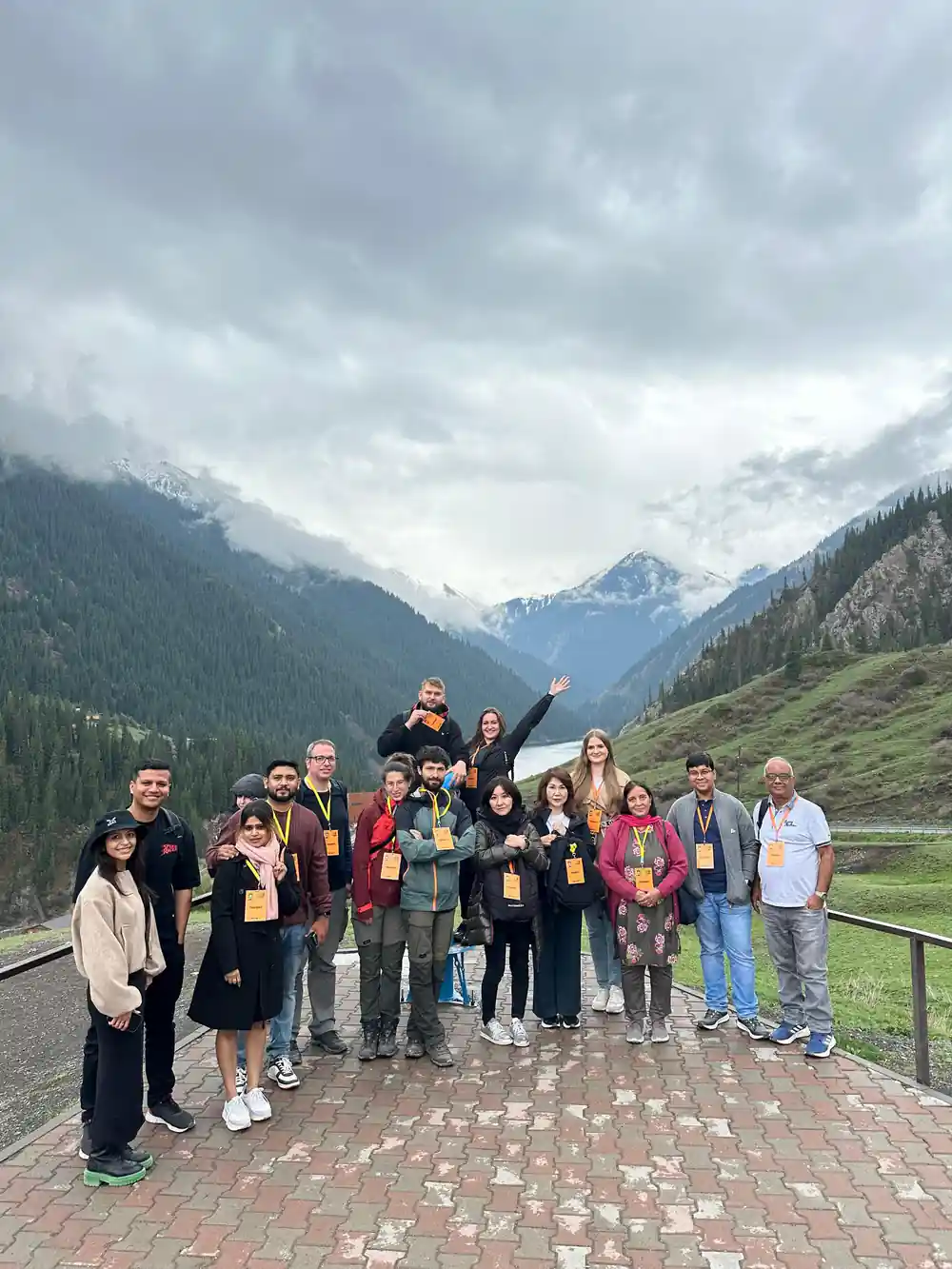 Group of tourists standing by mountain valley with lake