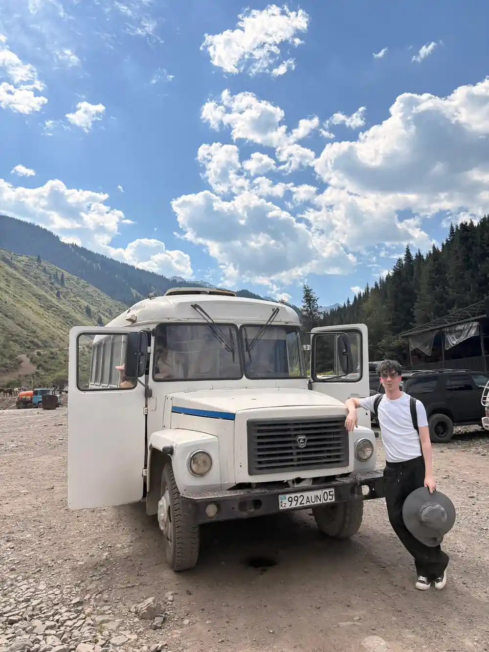 Man standing beside white Soviet-era truck in mountain valley