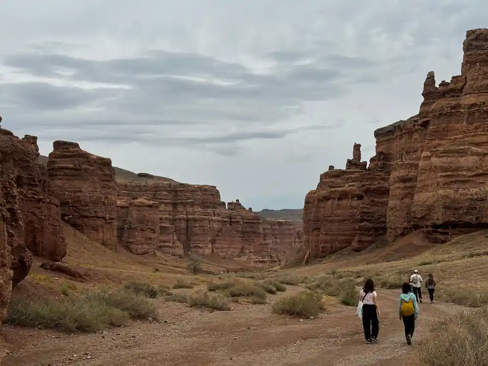Three hikers walking in red sandstone canyon landscape